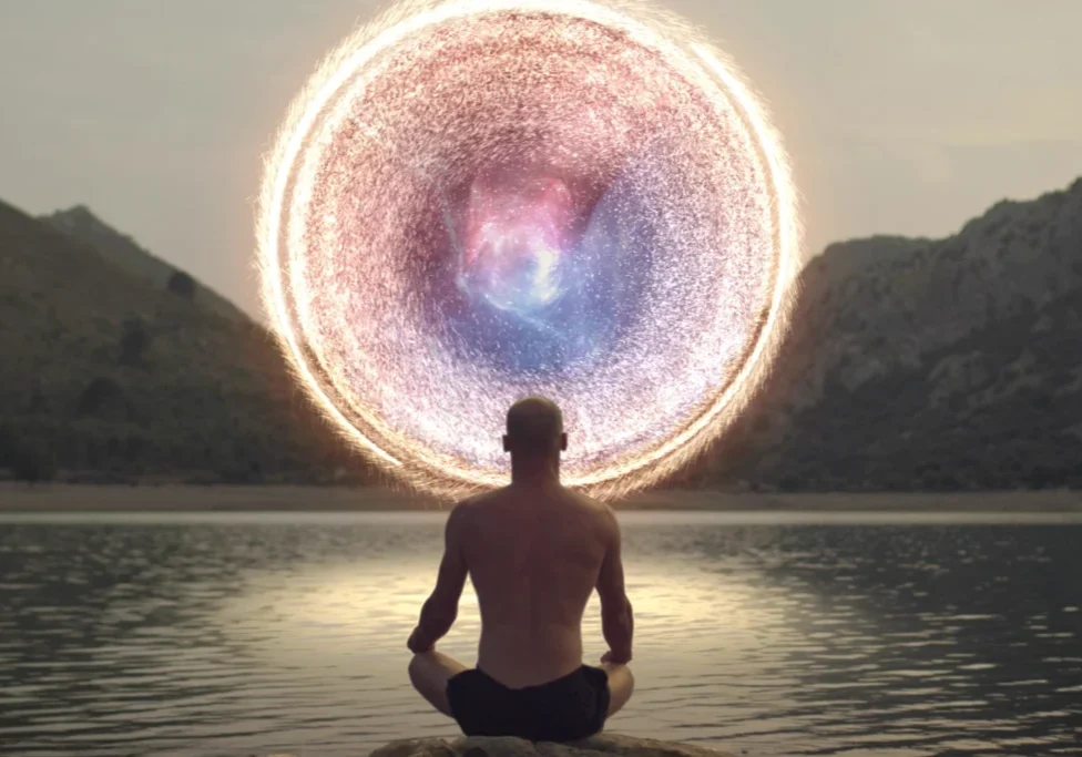 Person meditating by water with glowing circular light portal.